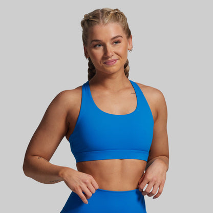 Woman wearing a blue sports bra and leggings on a gray background