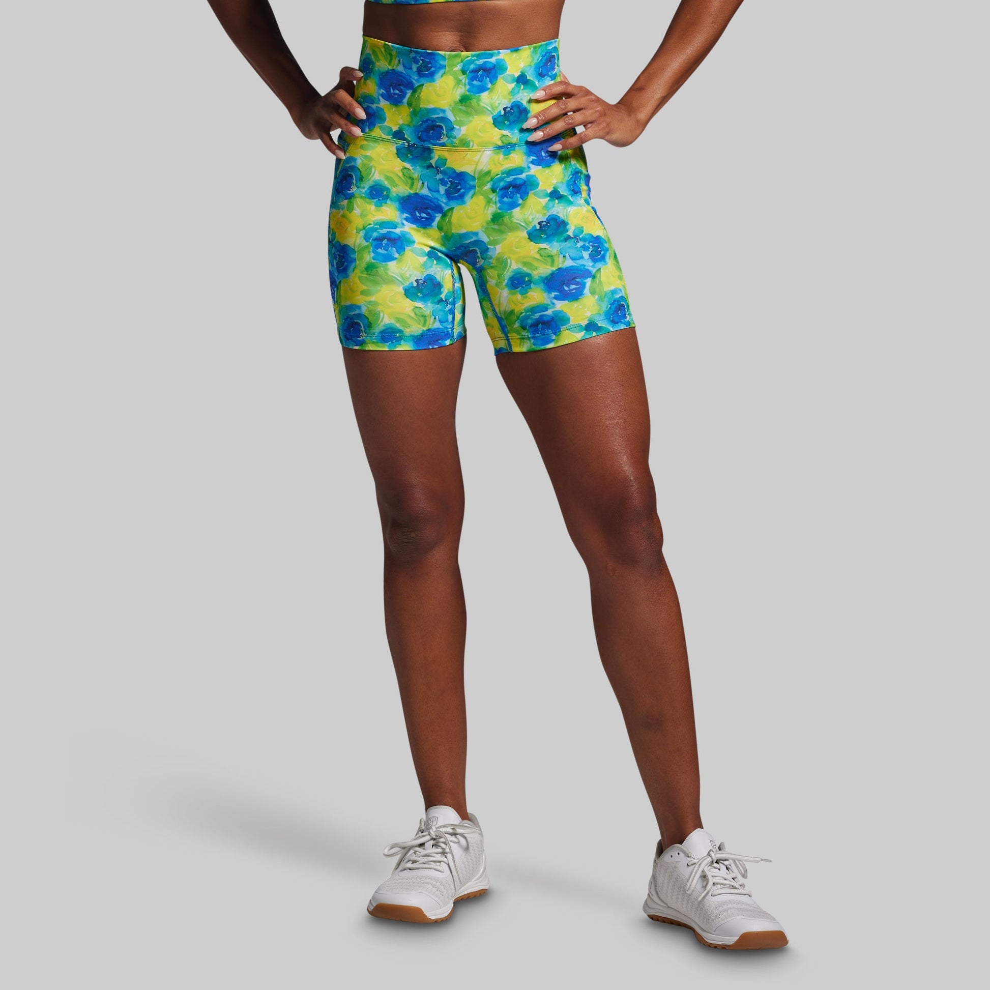 Person wearing colorful floral shorts on a gray background