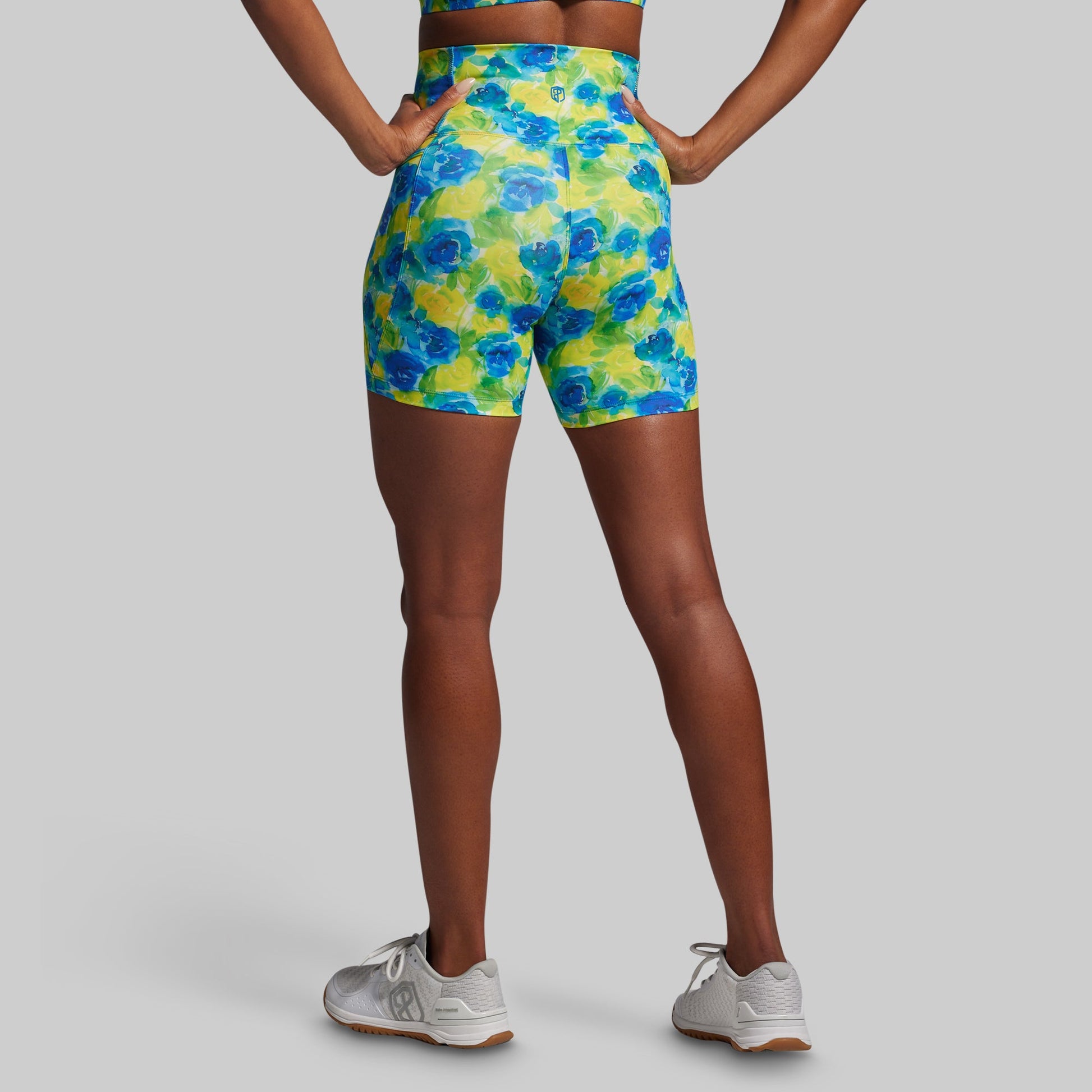 Person wearing colorful floral shorts on a plain background