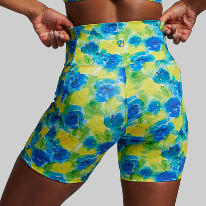 Floral patterned shorts being held up against a neutral background