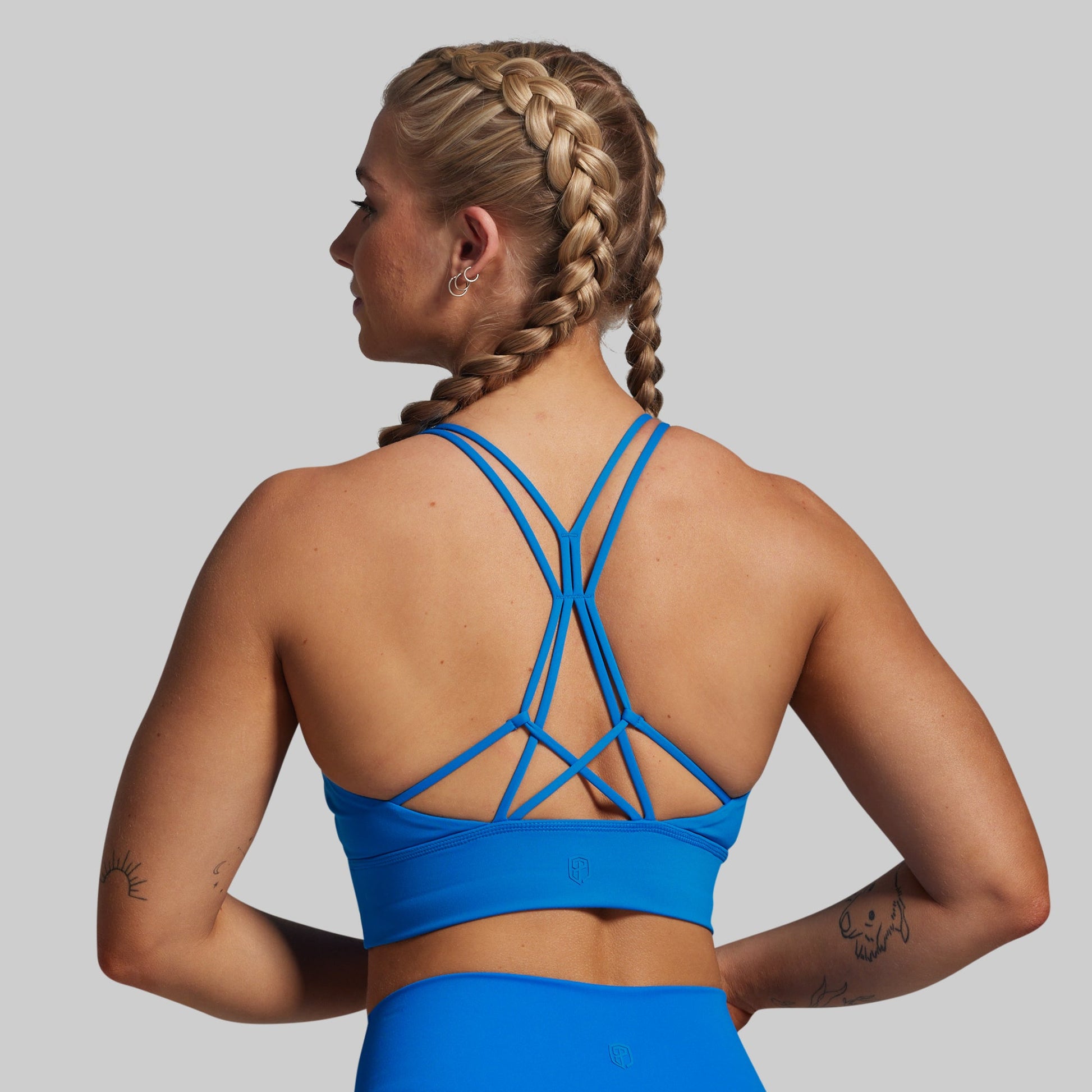 Woman wearing a blue sports bra and leggings on a gray background