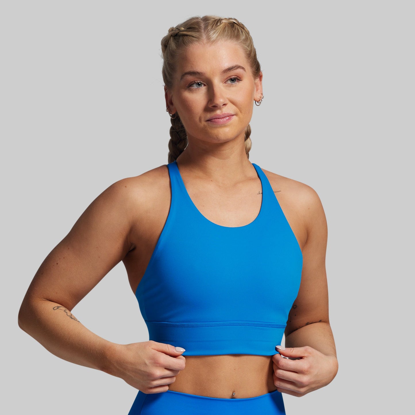Woman wearing a blue sports bra and leggings on a gray background