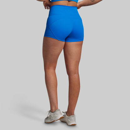 Person wearing bright blue high-waisted shorts on a gray background