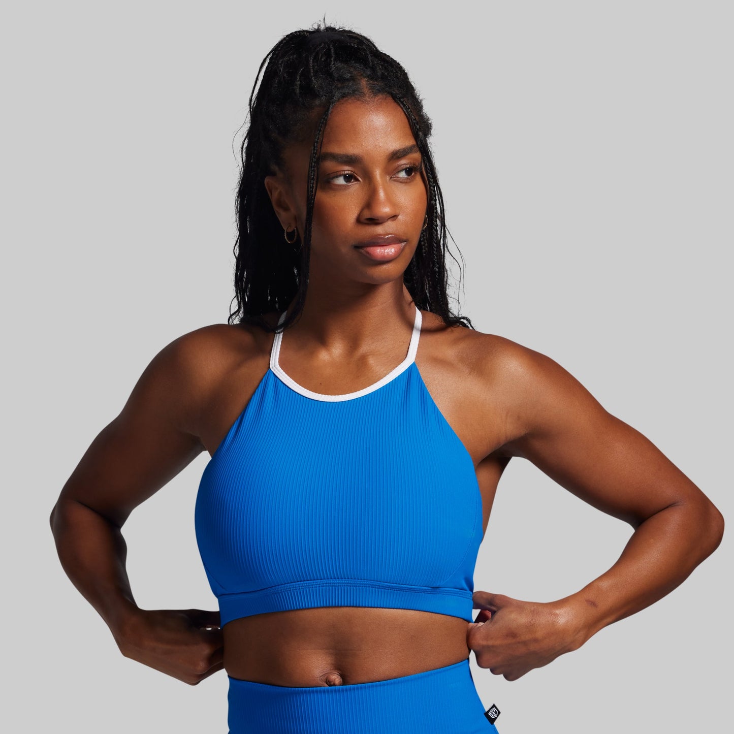 Woman wearing a blue sports bra and leggings on a gray background