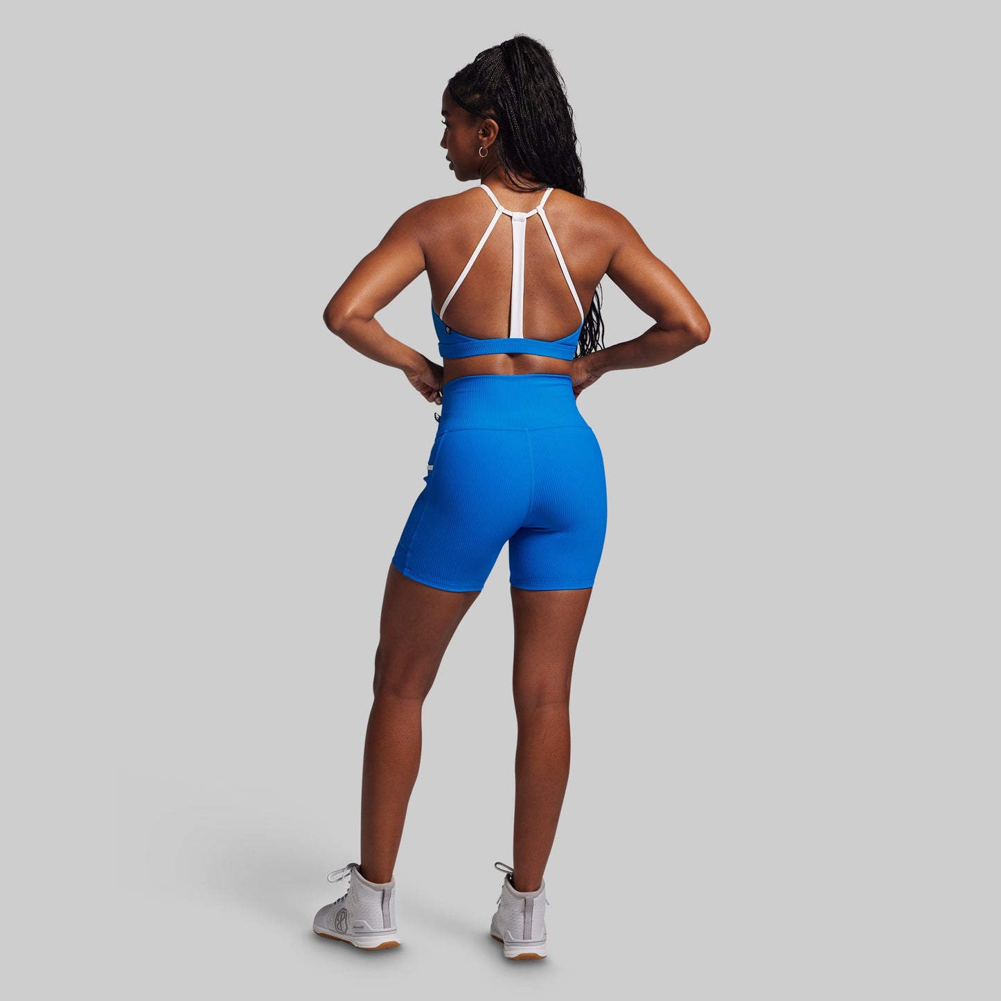 Person wearing a blue athletic outfit with white straps on a gray background