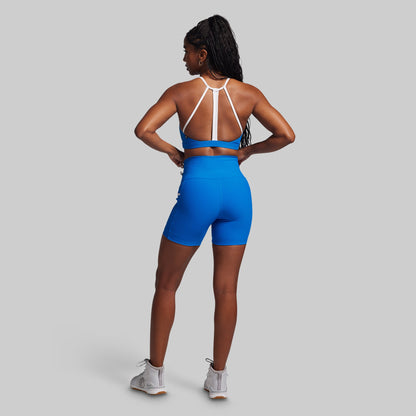 Person wearing a blue athletic outfit with white straps on a gray background