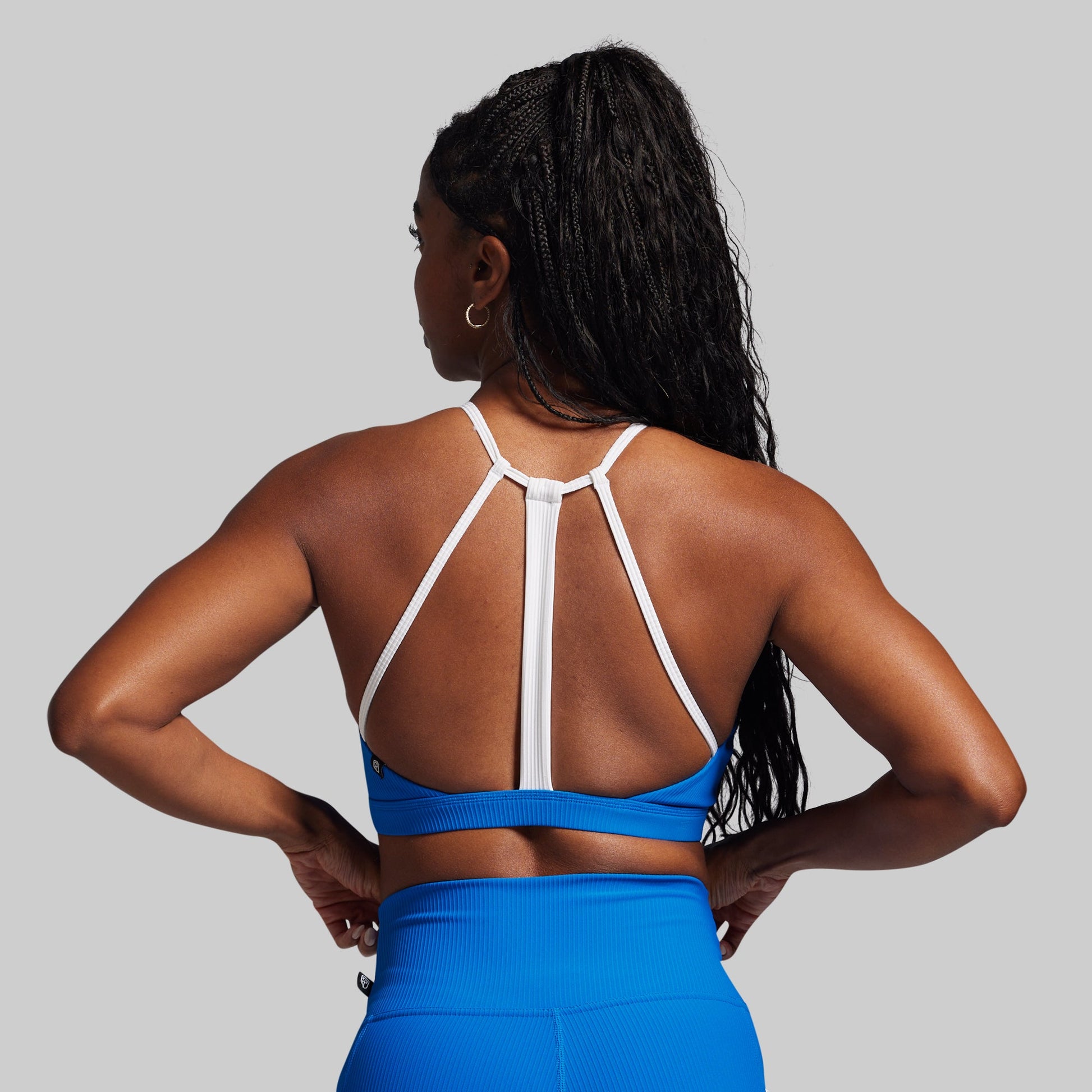 Person wearing a blue sports bra and leggings with a gray background