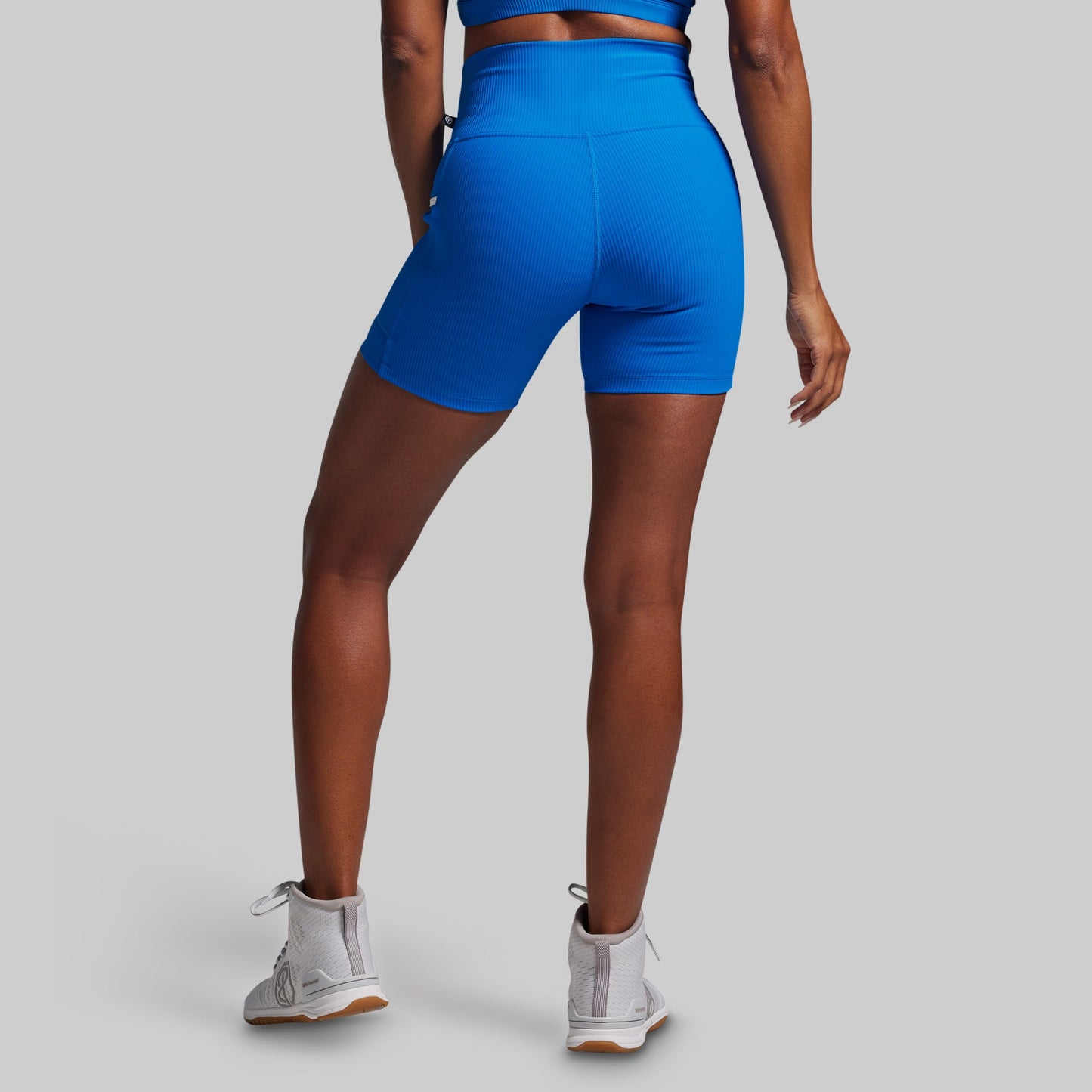 Person wearing blue athletic shorts on a gray background