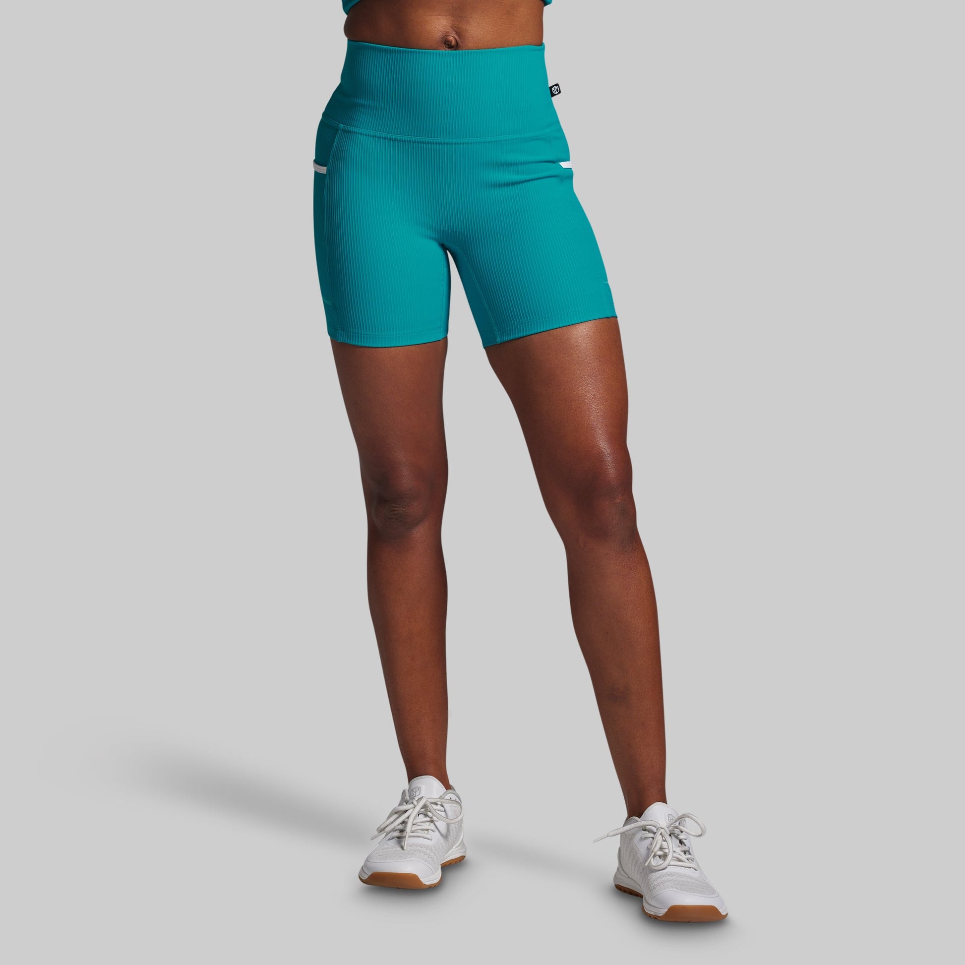 Teal athletic shorts worn by a person on a gray background