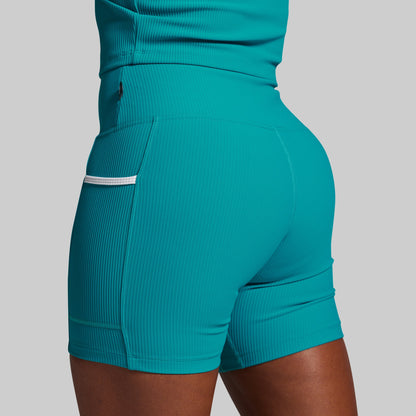 Teal athletic shorts with a pocket on a gray background