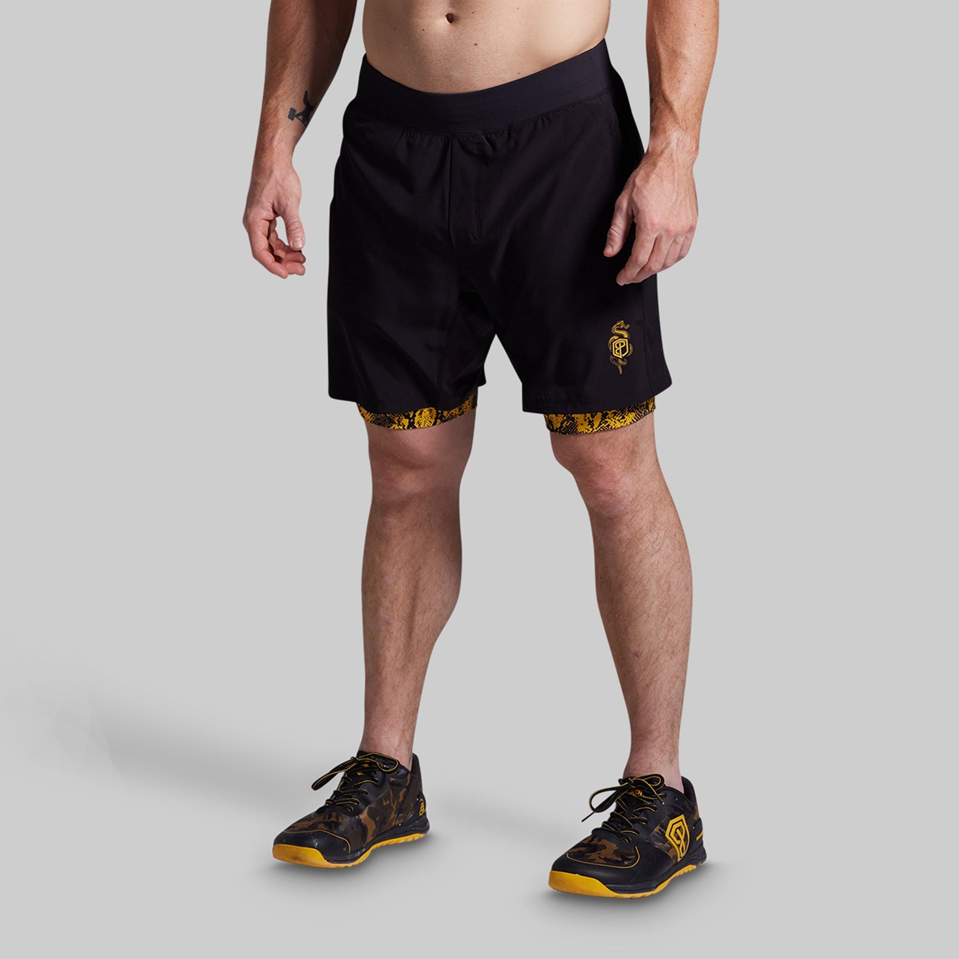Person wearing black athletic shorts with yellow accents on a gray background