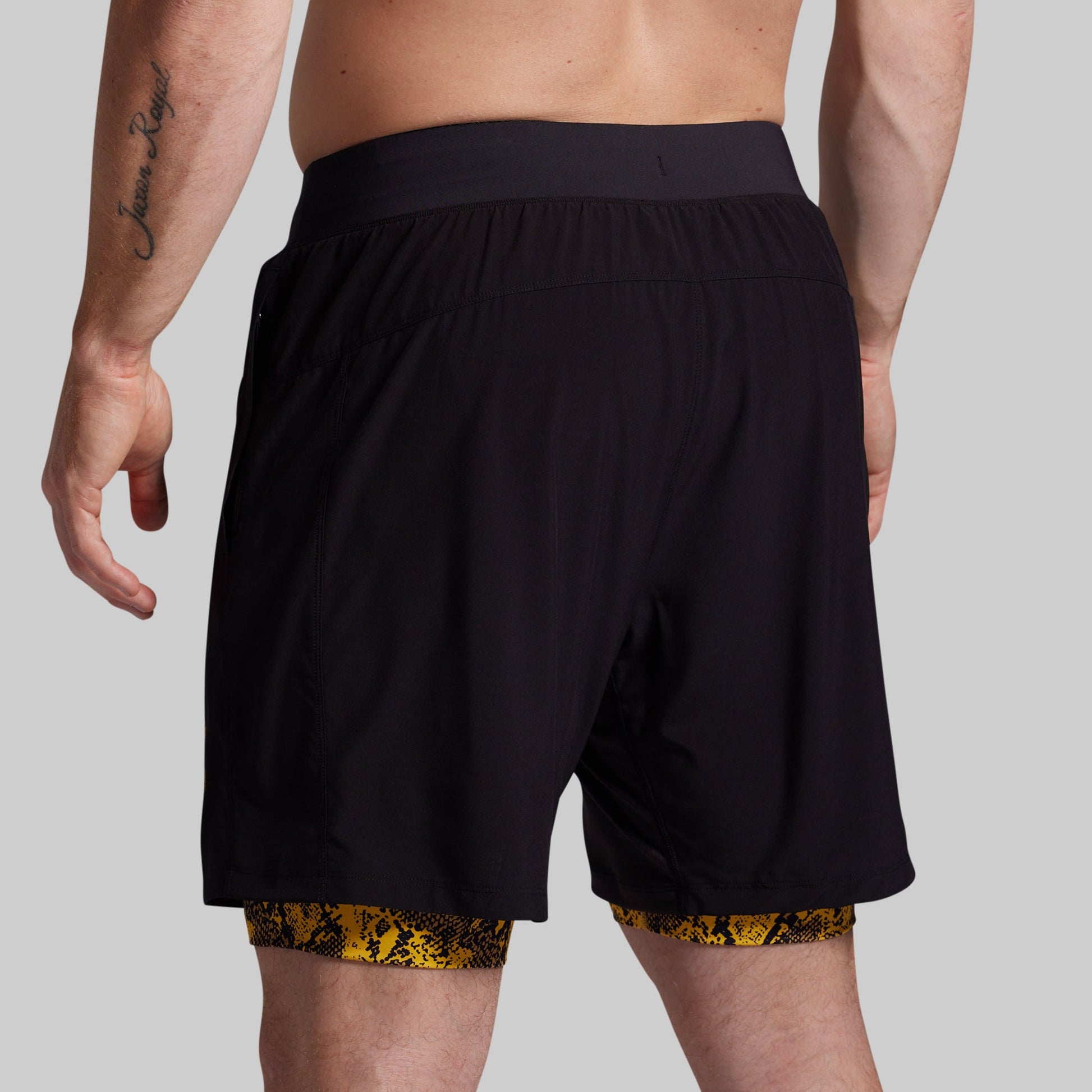 Black shorts with yellow pattern at the bottom worn by a person on a gray background