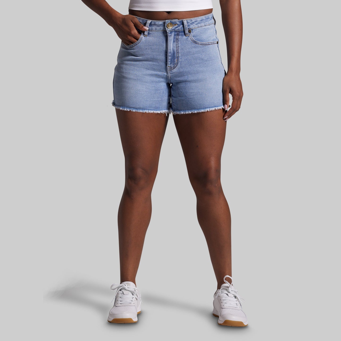 Person wearing light blue denim shorts on a gray background