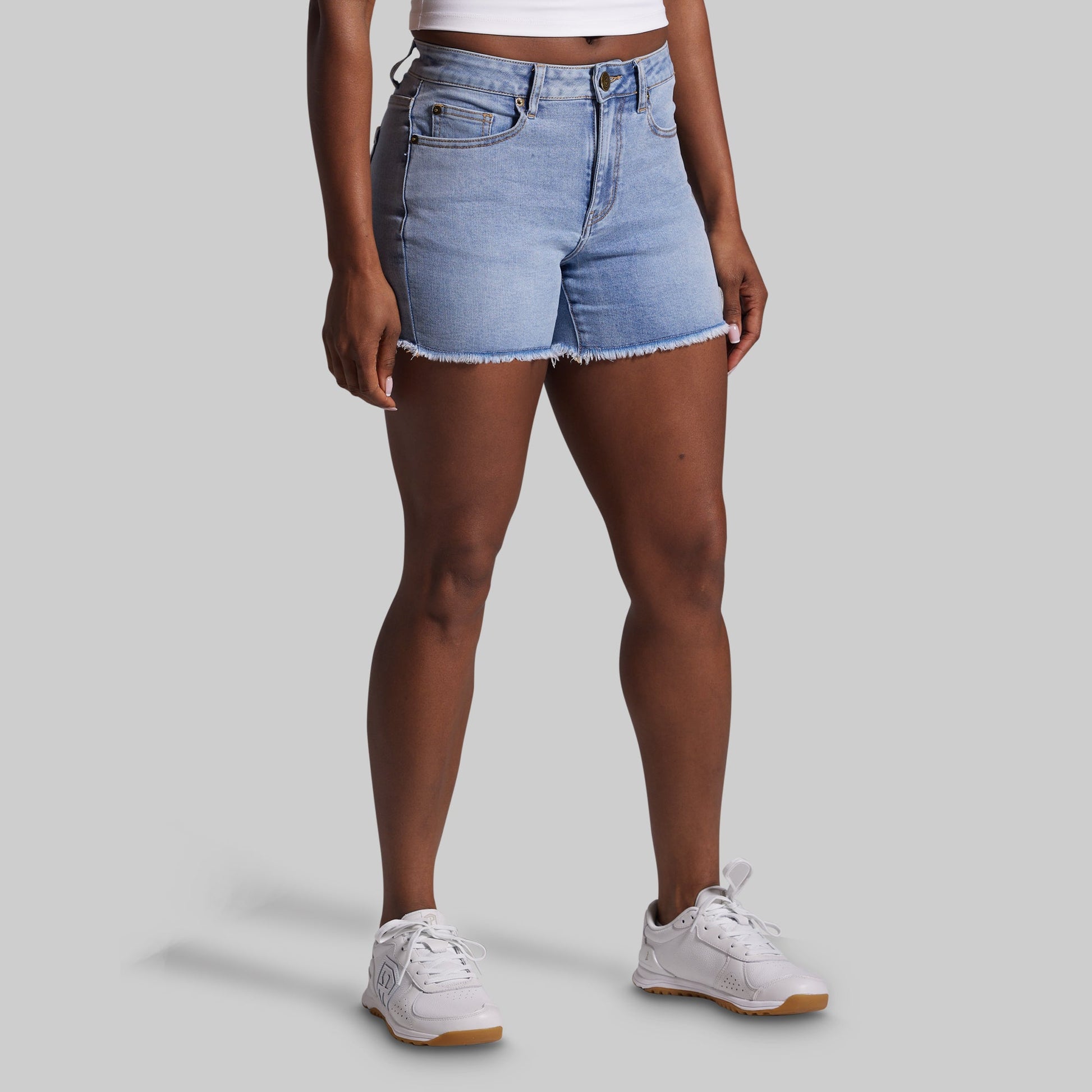 Person wearing light blue denim shorts on a gray background
