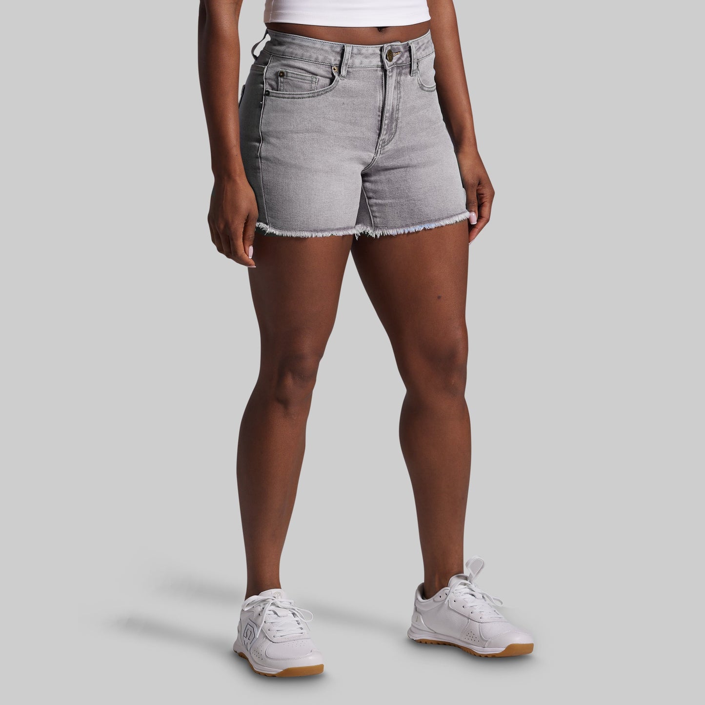 Person wearing gray denim shorts on a plain background