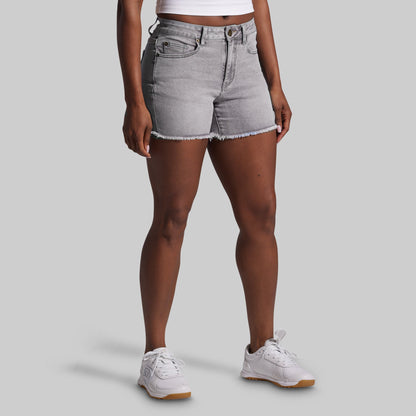 Person wearing gray denim shorts on a plain background