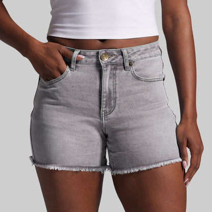 Person wearing gray denim shorts on a plain background