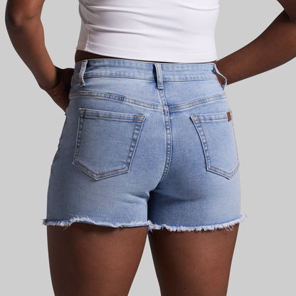 Person wearing light blue denim shorts on a plain background
