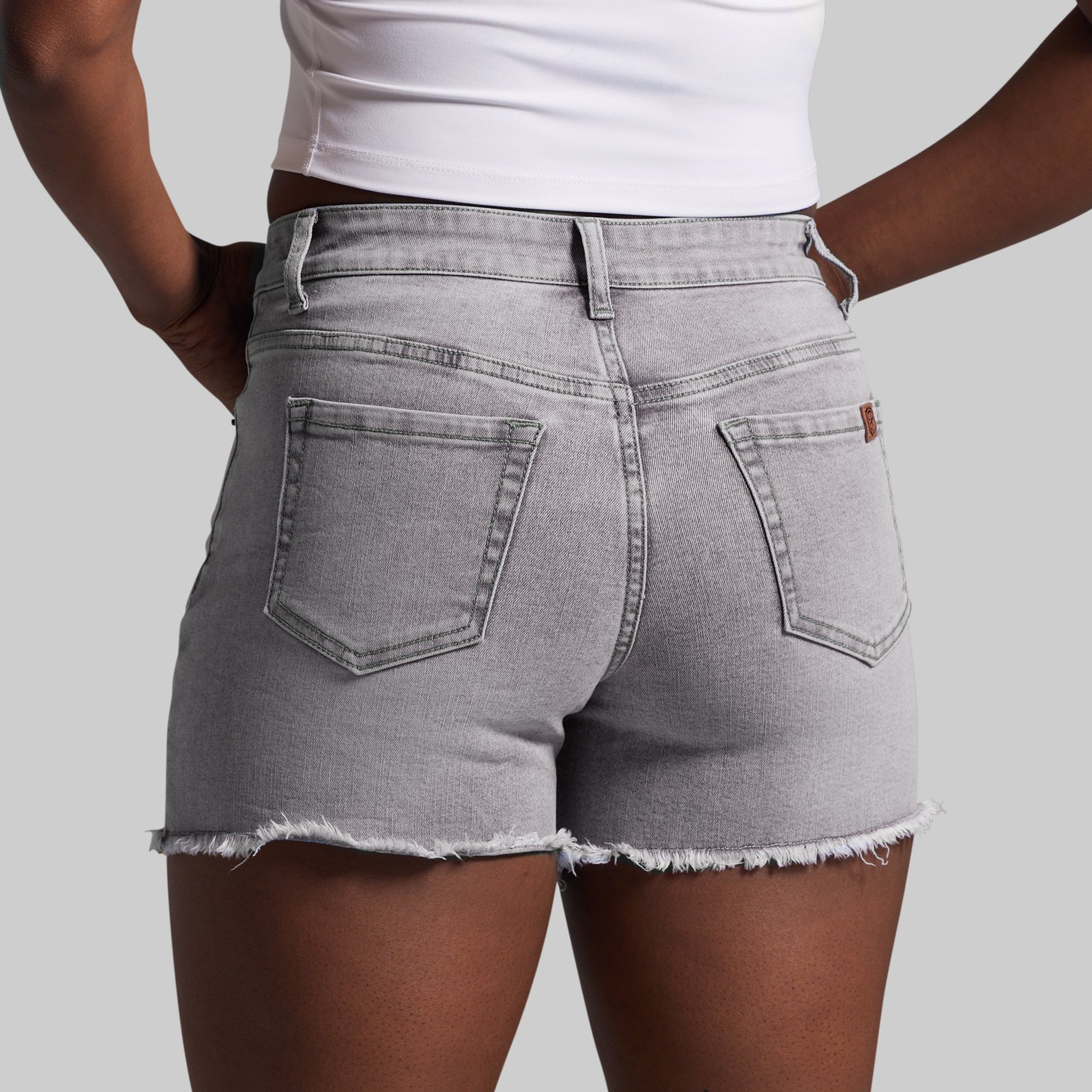 Person wearing gray denim shorts on a plain background
