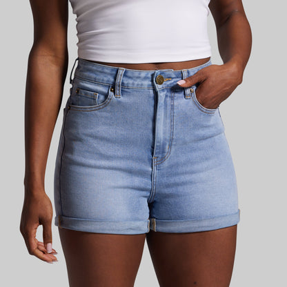 Person wearing light blue denim shorts on a plain background