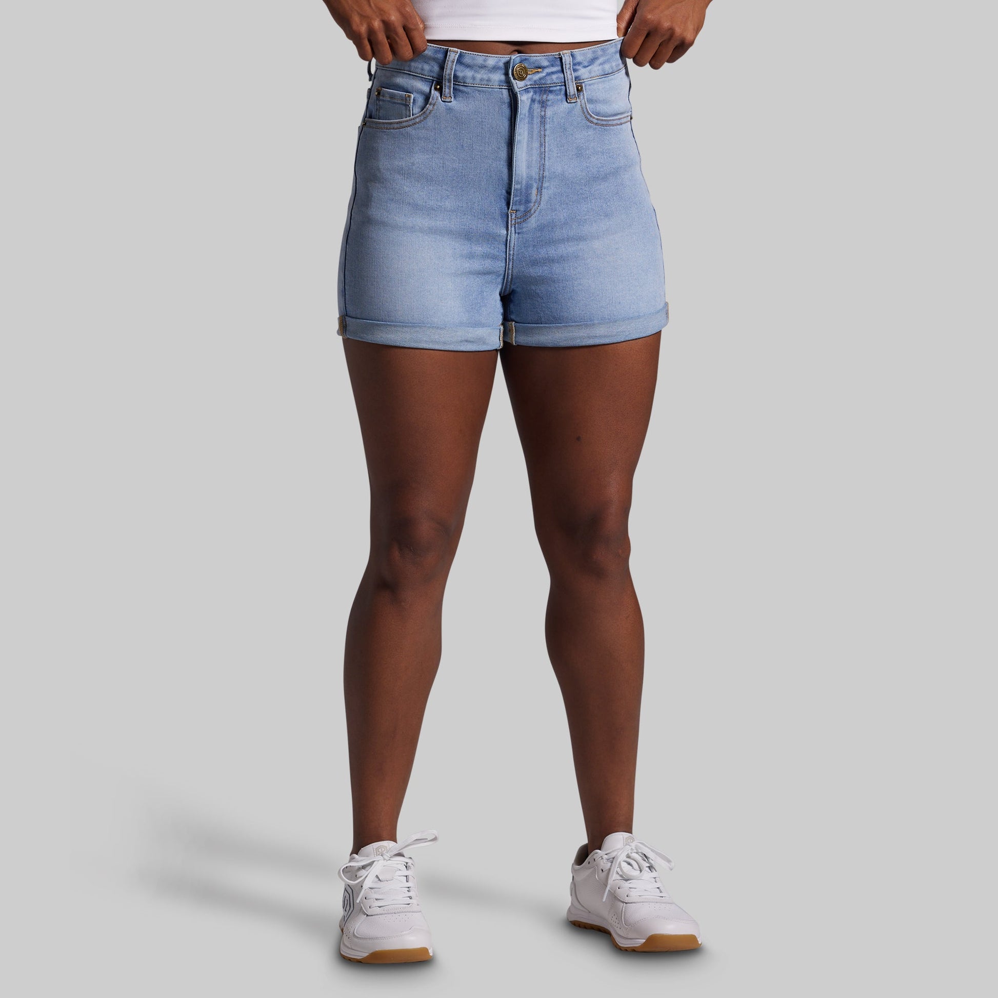 Person wearing light blue denim shorts on a gray background