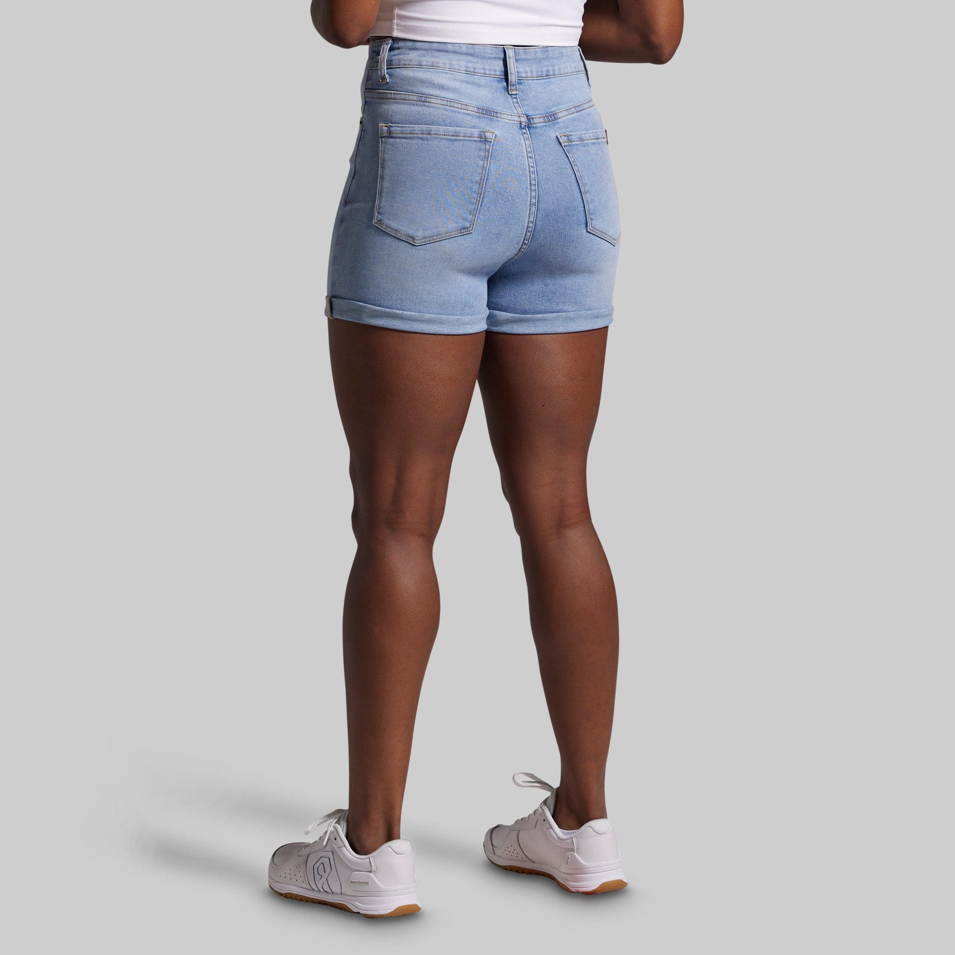 Person wearing light blue denim shorts on a gray background