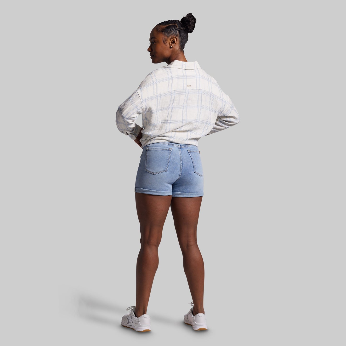 Person wearing a white shirt and light blue denim shorts on a gray background