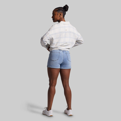 Person wearing a white shirt and light blue denim shorts on a gray background