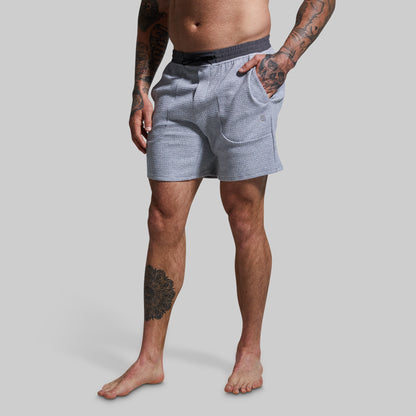 Person wearing light gray textured shorts on a plain background