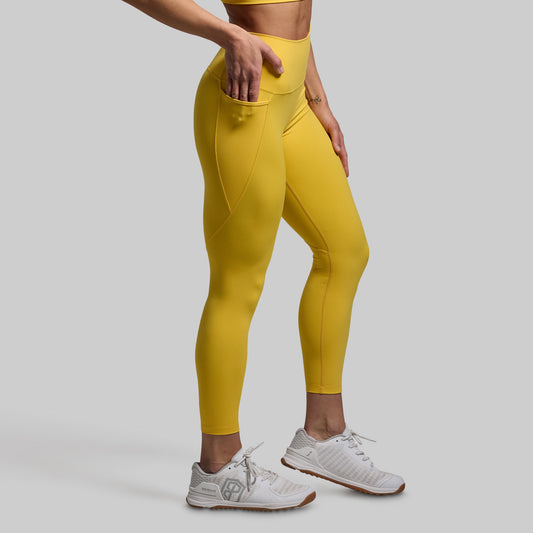 Person wearing yellow leggings and white sneakers on a light gray background