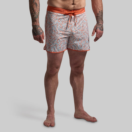 Person wearing patterned swim shorts on a plain background