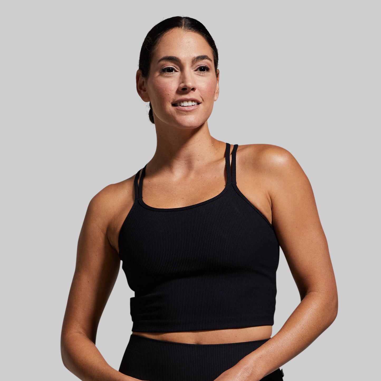 Woman wearing a black sports bra against a plain background