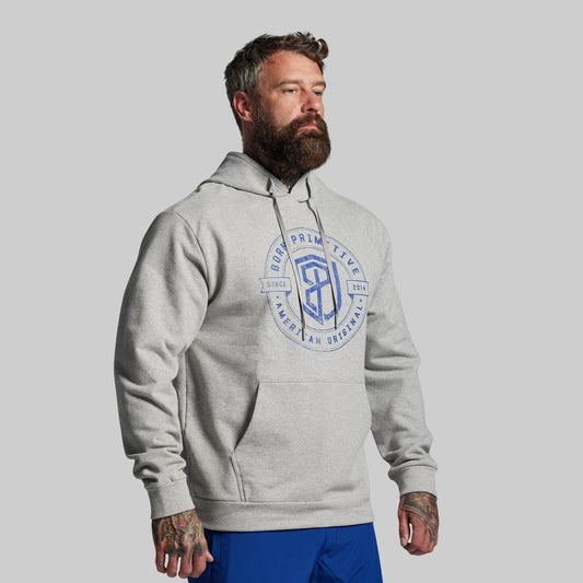 Man wearing a gray hoodie with a logo on a gray background