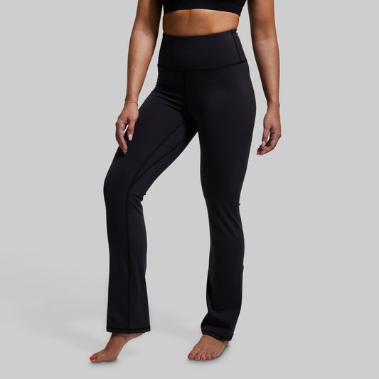 Person wearing black yoga pants on a gray background
