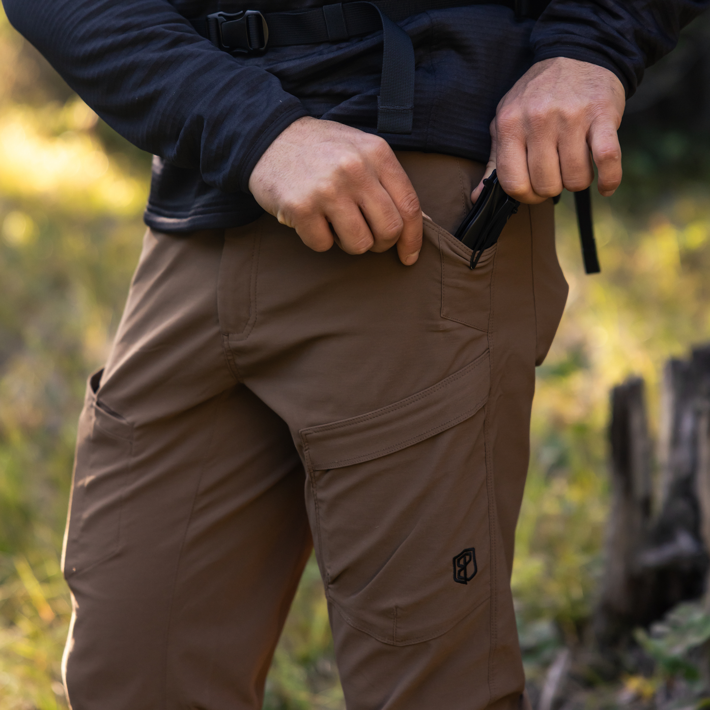 Person wearing brown pants with a logo in a natural setting