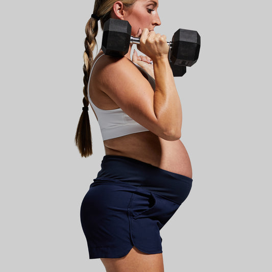 Woman lifting a dumbbell against a plain background