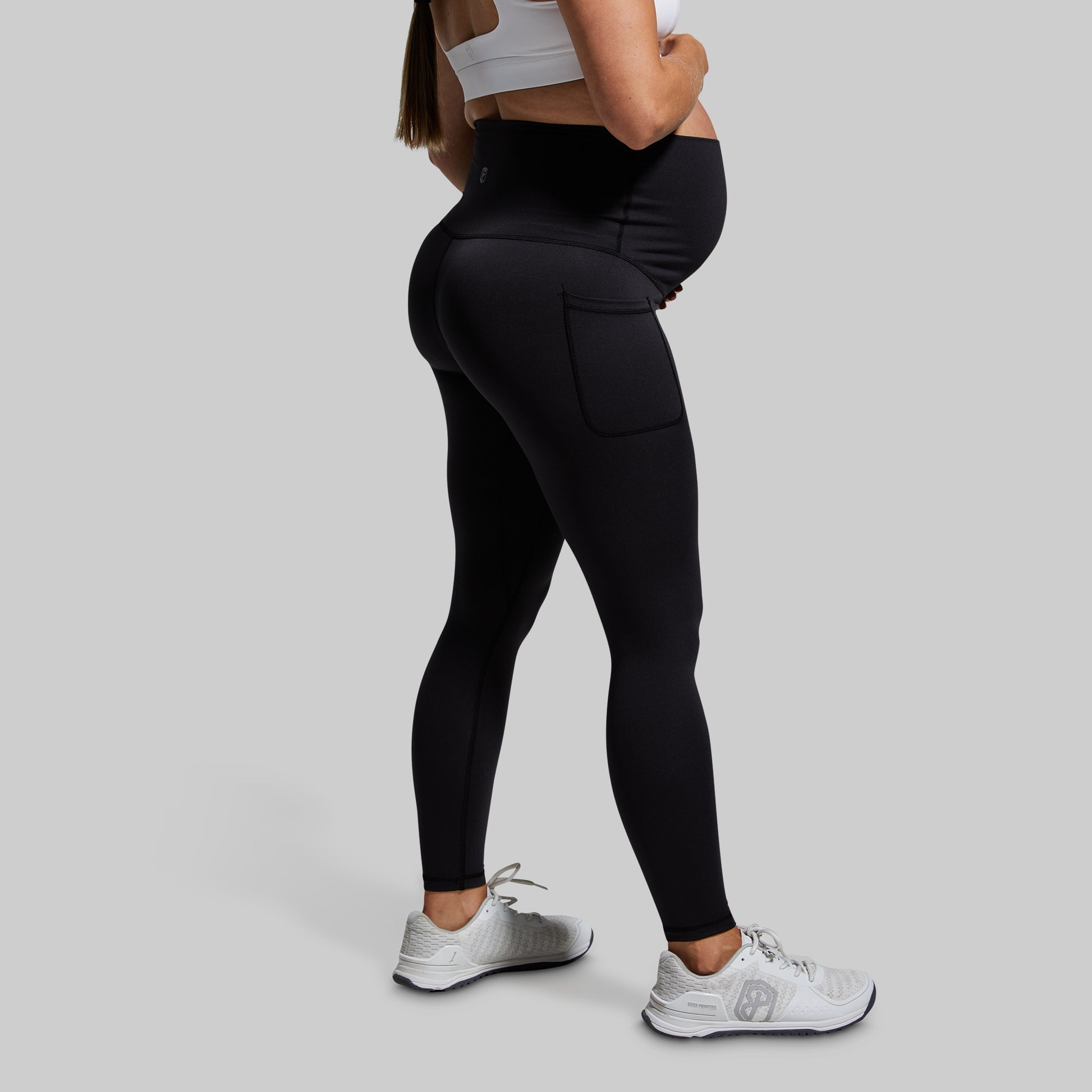 Person wearing black leggings and white sneakers on a gray background