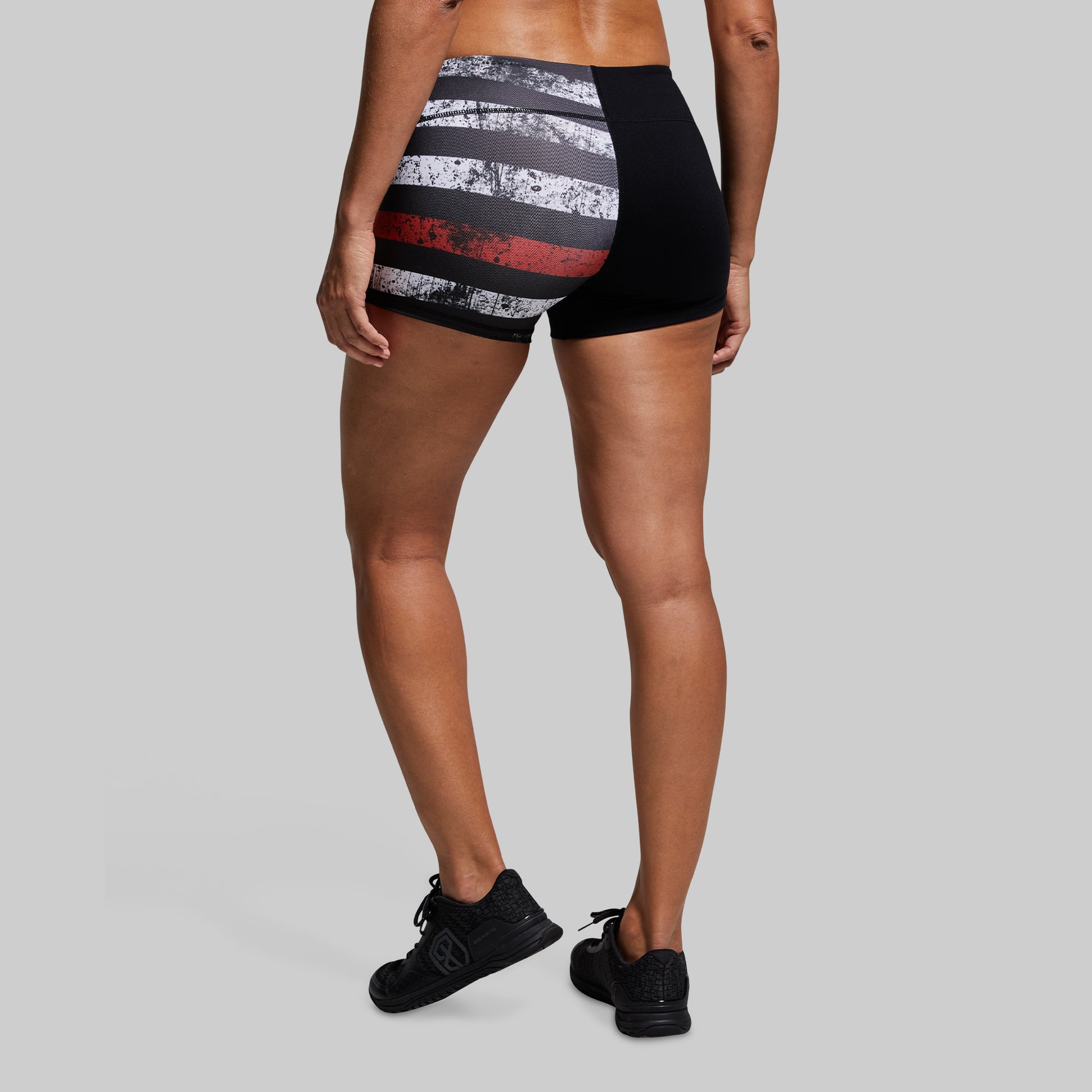 Person wearing black and red striped athletic shorts on a gray background