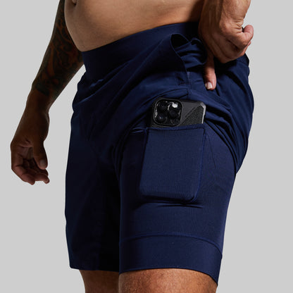 Navy blue athletic shorts with a pocket on a gray background