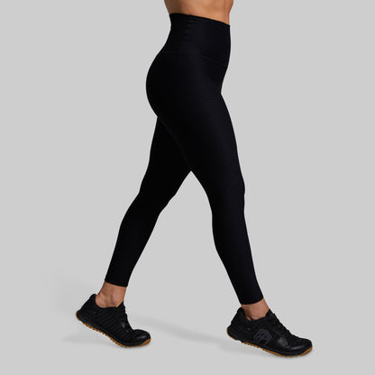 Person wearing black leggings on a gray background