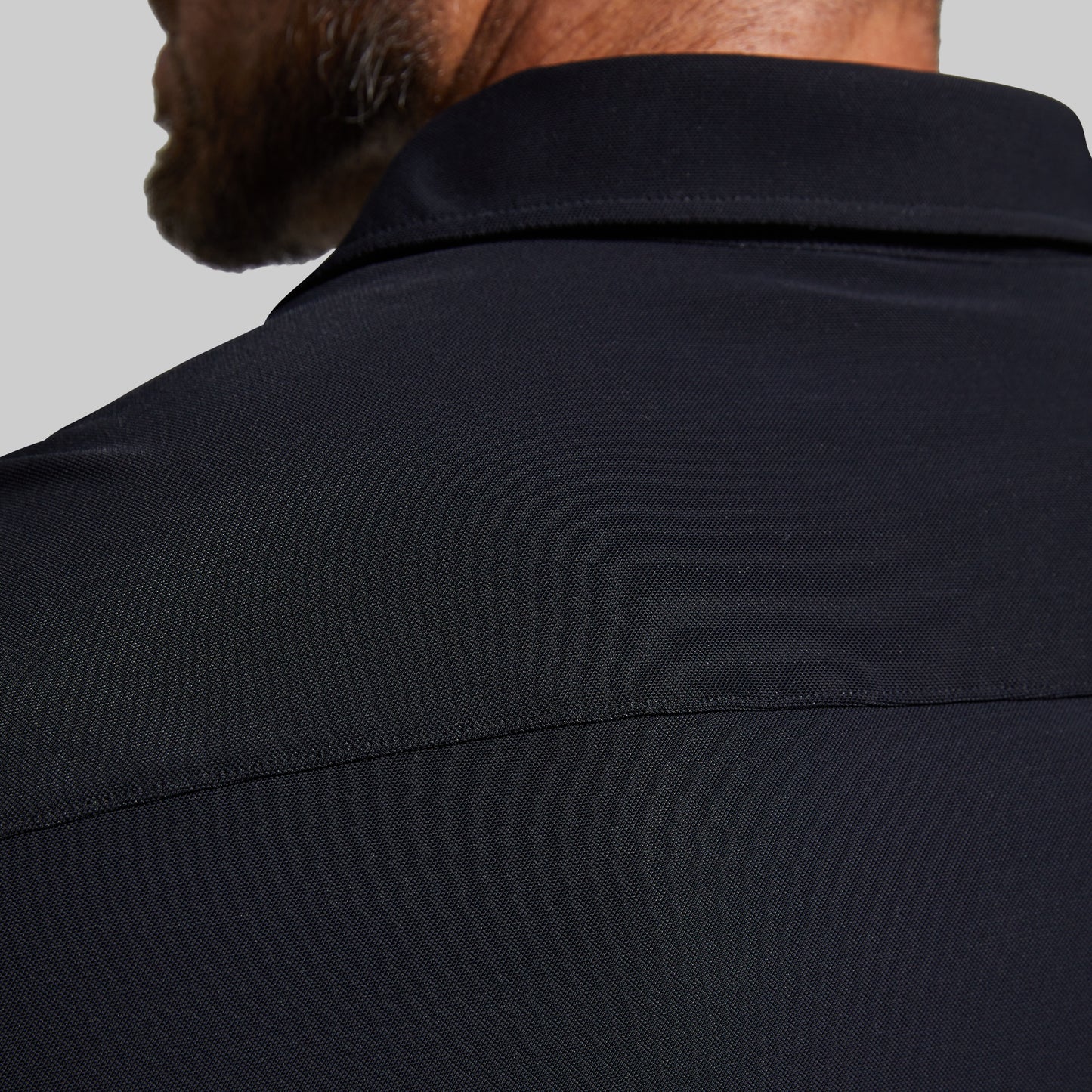 Close-up of a person wearing a black shirt against a gray background