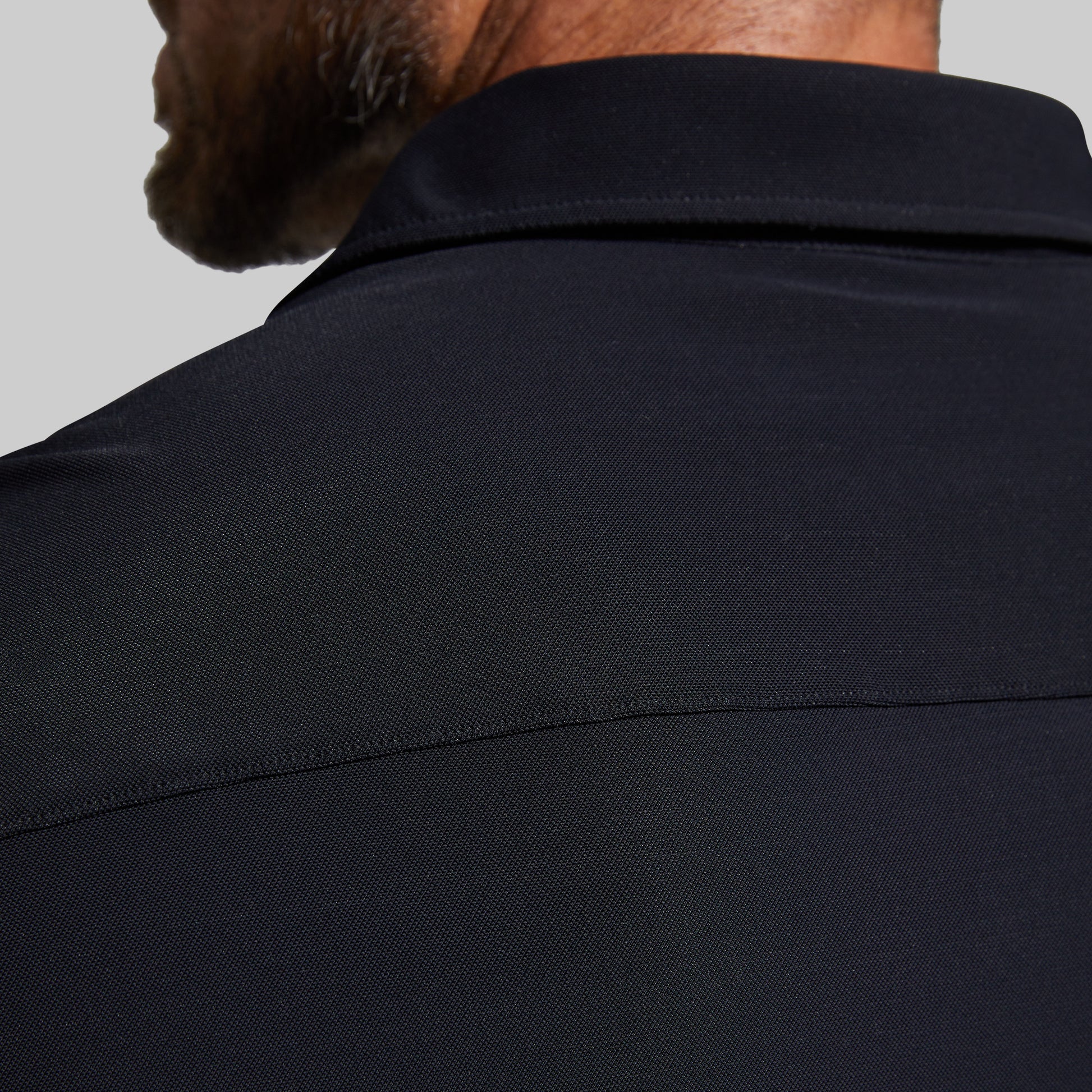 Close-up of a person wearing a black shirt against a gray background