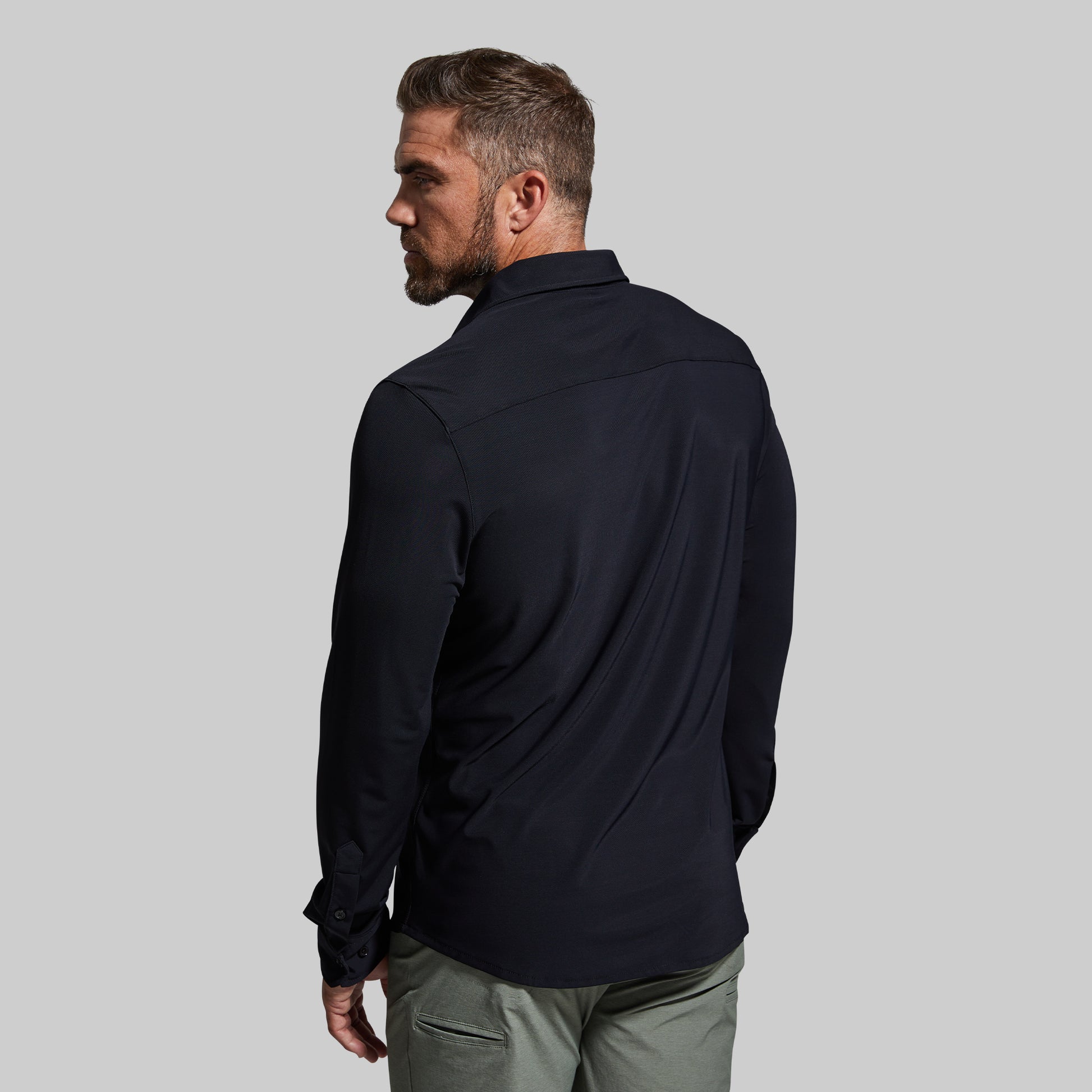 Man wearing a black shirt and green pants on a gray background