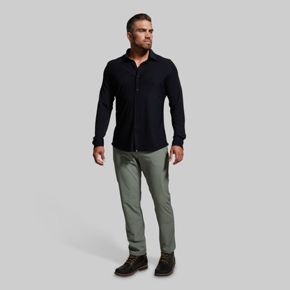 Man wearing a black long-sleeve shirt and gray pants on a light gray background