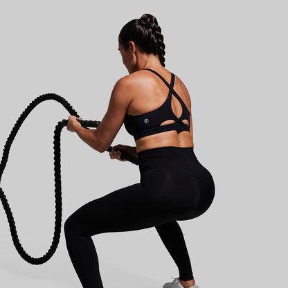 Person in black athletic wear holding a rope against a gray background