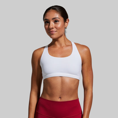 Woman wearing a white sports bra and red leggings on a gray background