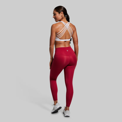 Person wearing a red athletic outfit with a white sports bra on a gray background