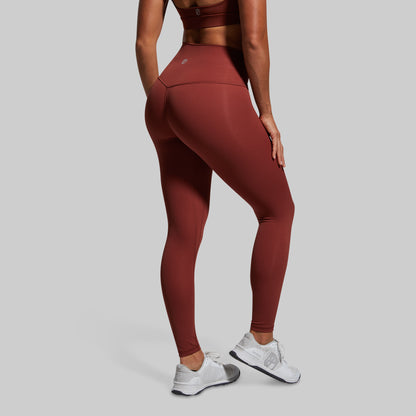 Person wearing maroon leggings and white sneakers on a gray background