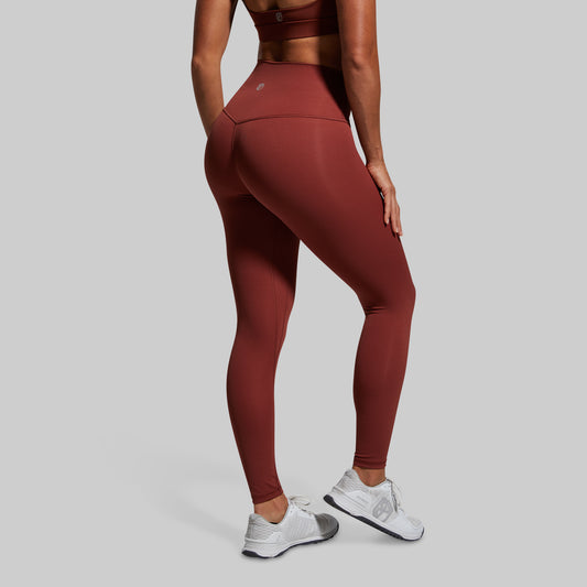 Person wearing maroon leggings and white sneakers on a gray background