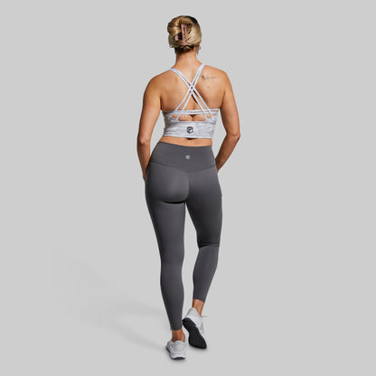 Woman wearing a sports bra and leggings on a plain background